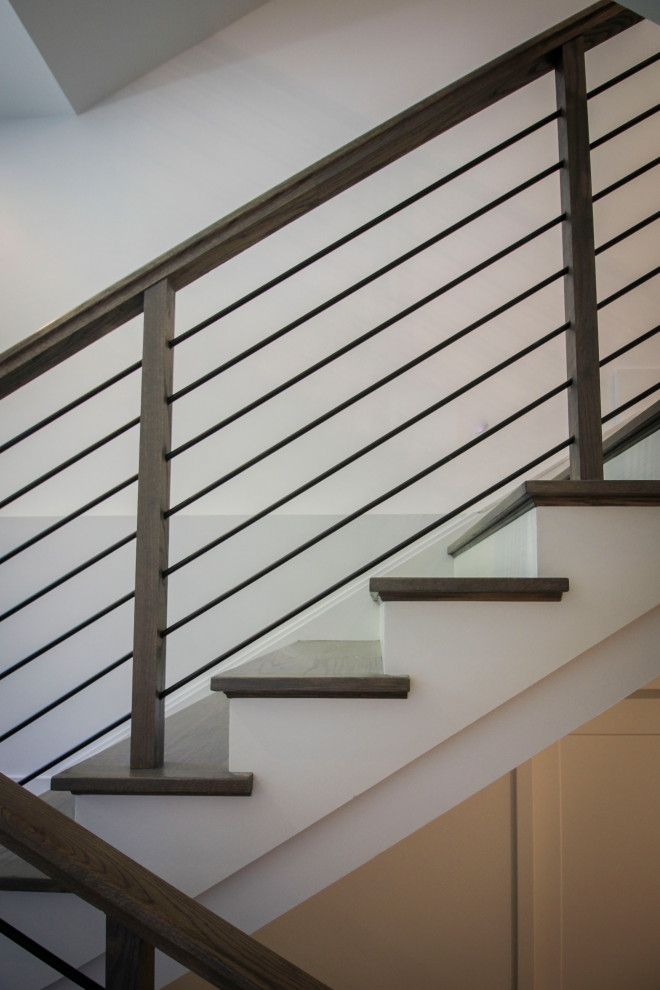 Photo of a medium sized classic wood u-shaped metal railing staircase in DC Metro with wood risers and panelled walls.
