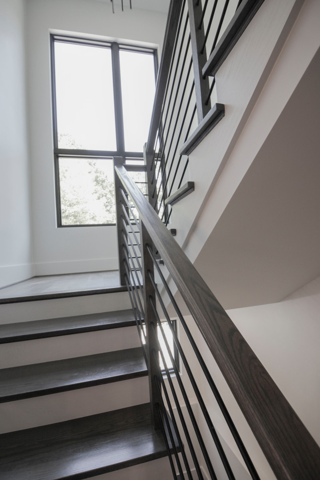 На фото: п-образная деревянная лестница среднего размера в стиле неоклассика (современная классика) с деревянными ступенями, металлическими перилами и панелями на части стены
