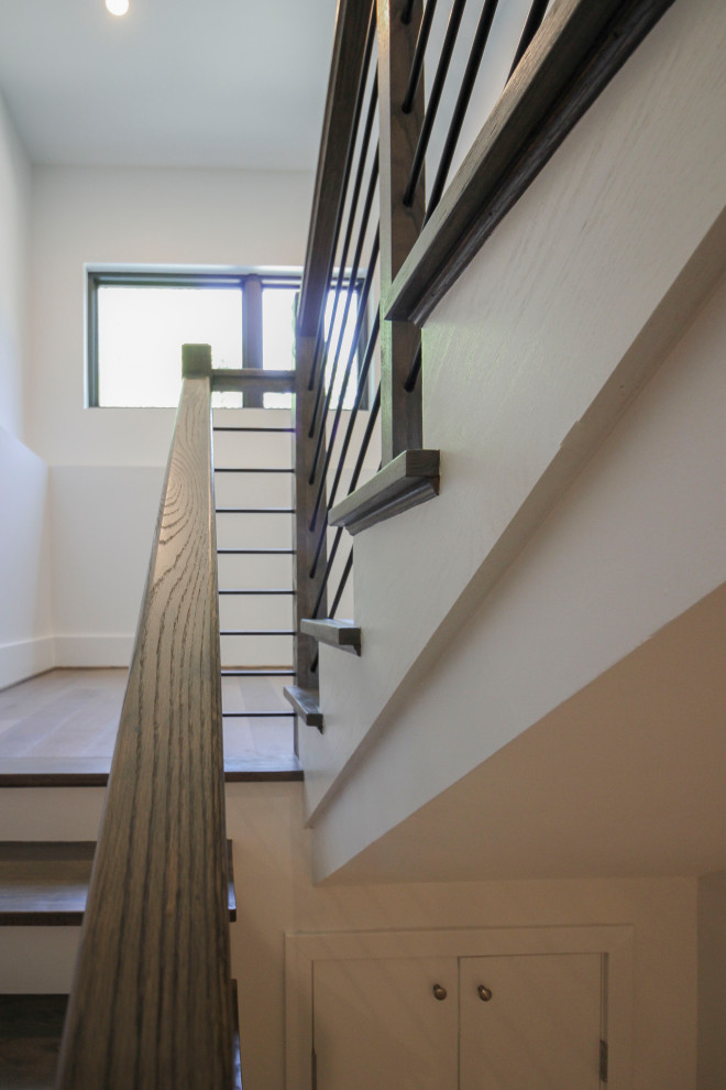 Cette image montre un escalier traditionnel en U de taille moyenne avec des marches en bois, des contremarches en bois, un garde-corps en métal et du lambris.
