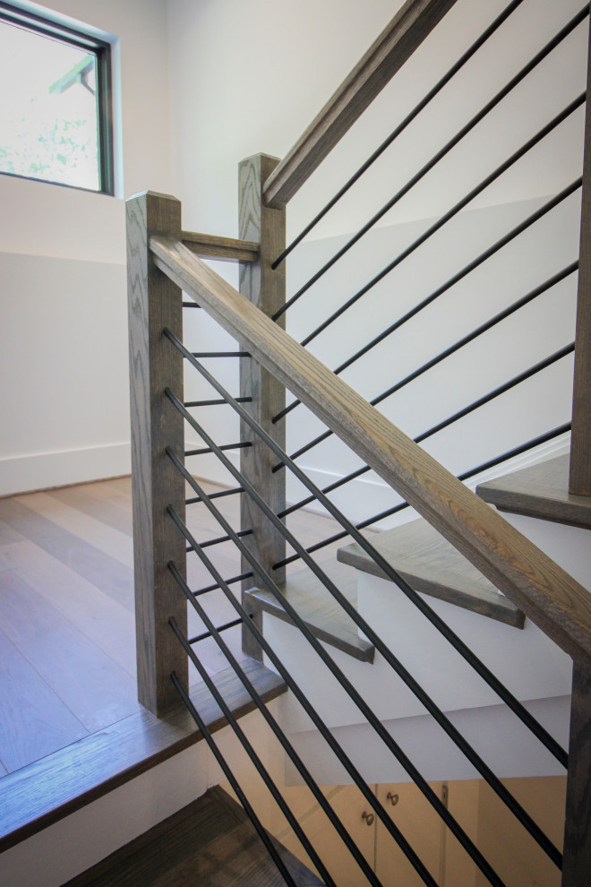 Пример оригинального дизайна: п-образная деревянная лестница среднего размера в стиле неоклассика (современная классика) с деревянными ступенями, металлическими перилами и панелями на части стены