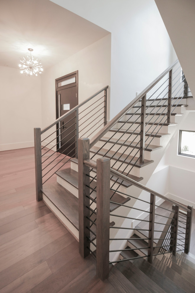 На фото: п-образная деревянная лестница среднего размера в стиле неоклассика (современная классика) с деревянными ступенями, металлическими перилами и панелями на части стены с