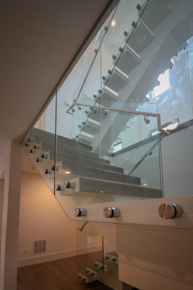 Idées déco pour un très grand escalier flottant moderne avec des marches en bois et un garde-corps en verre.