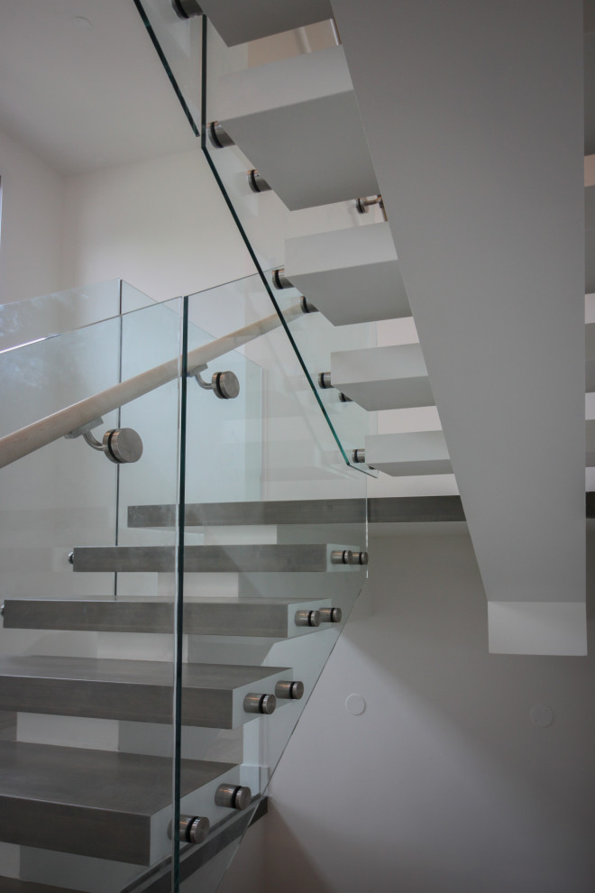 Свежая идея для дизайна: огромная лестница на больцах в стиле модернизм с деревянными ступенями и стеклянными перилами - отличное фото интерьера
