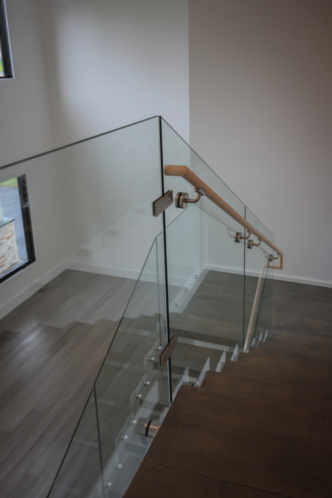 Ejemplo de escalera suspendida minimalista extra grande con escalones de madera y barandilla de vidrio