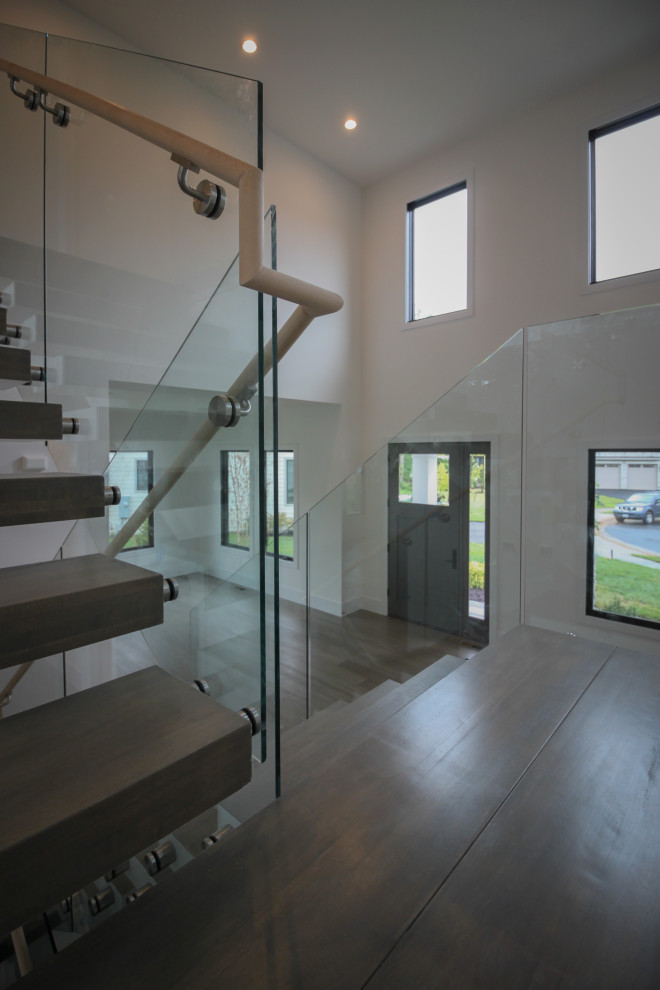 Ejemplo de escalera suspendida moderna extra grande con escalones de madera y barandilla de vidrio