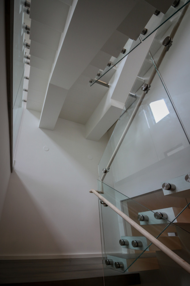 Пример оригинального дизайна: огромная лестница на больцах в стиле модернизм с деревянными ступенями и стеклянными перилами