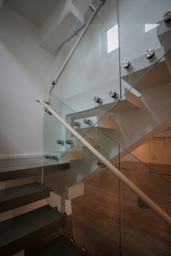Modern inredning av en mycket stor flytande trappa i trä, med räcke i glas
