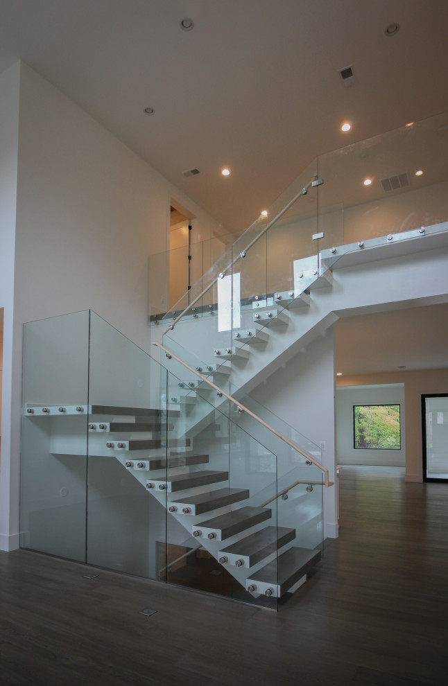 Réalisation d'un très grand escalier flottant minimaliste avec des marches en bois et un garde-corps en verre.