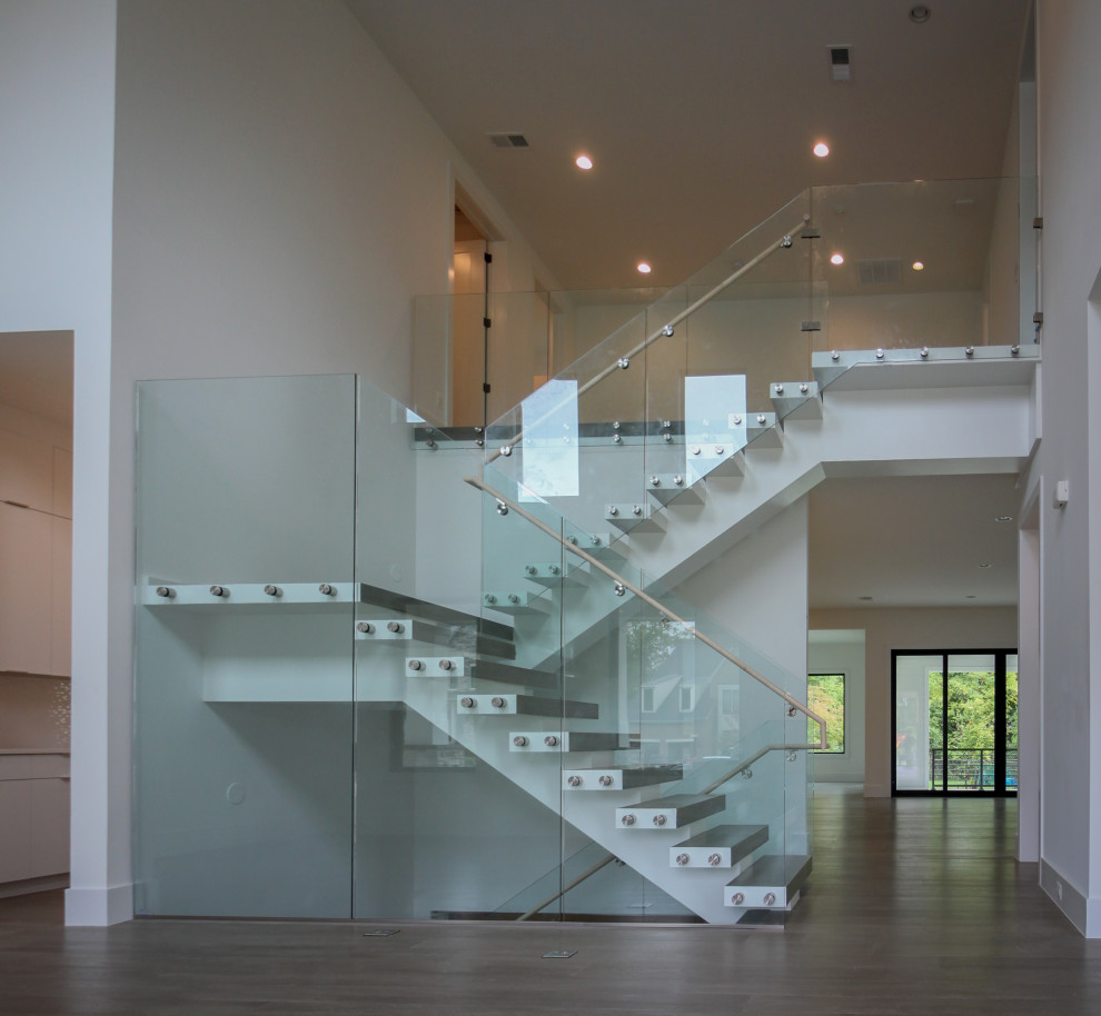На фото: огромная лестница на больцах в стиле модернизм с деревянными ступенями и стеклянными перилами