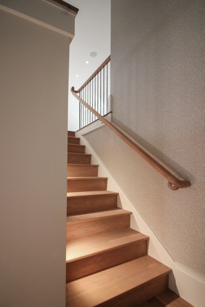 На фото: большая п-образная деревянная лестница в стиле модернизм с деревянными ступенями, металлическими перилами и обоями на стенах с
