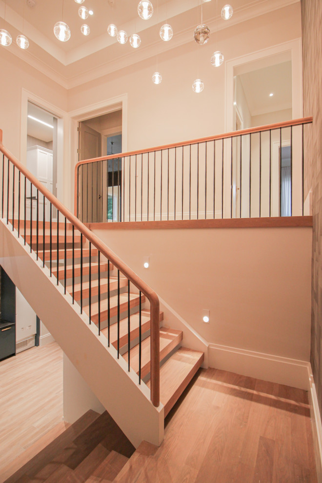 Large modern wood u-shaped metal railing staircase in DC Metro with wood risers and wallpapered walls.