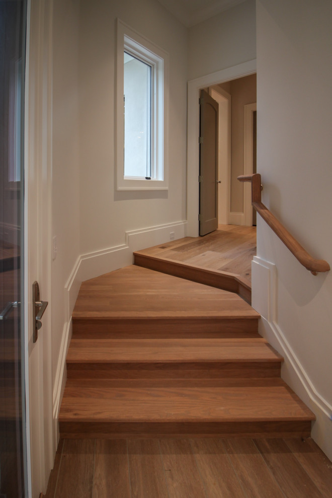 Imagen de escalera en U minimalista grande con escalones de madera, contrahuellas de madera, barandilla de metal y papel pintado