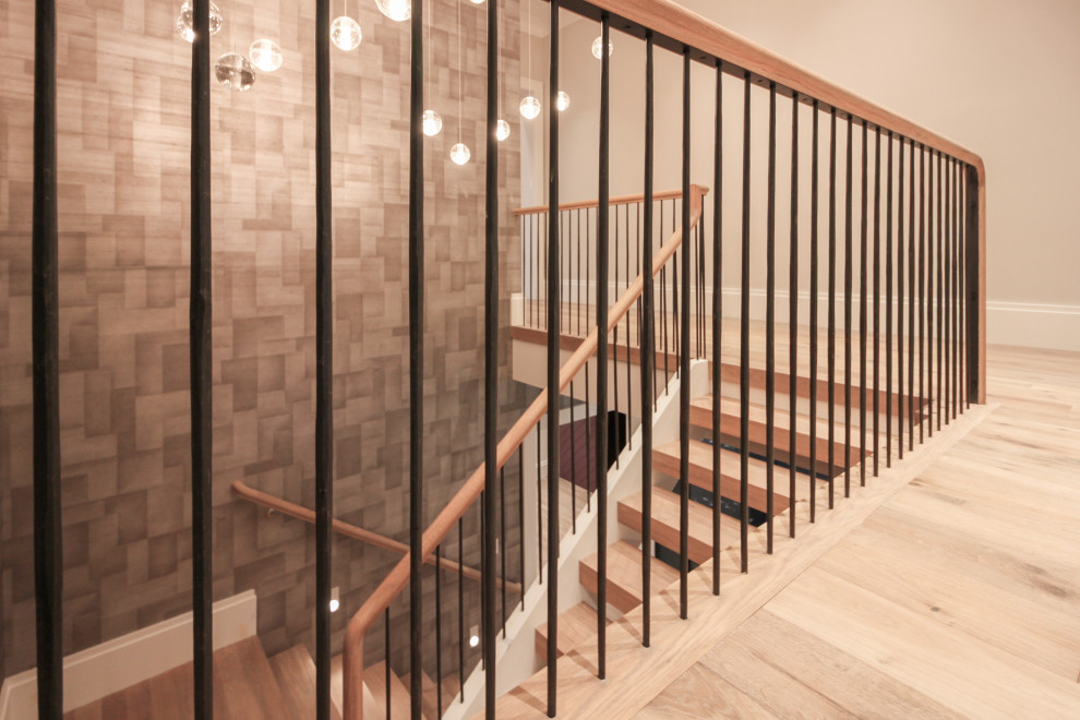 Exemple d'un grand escalier moderne en U avec des marches en bois, des contremarches en bois, un garde-corps en métal et du papier peint.