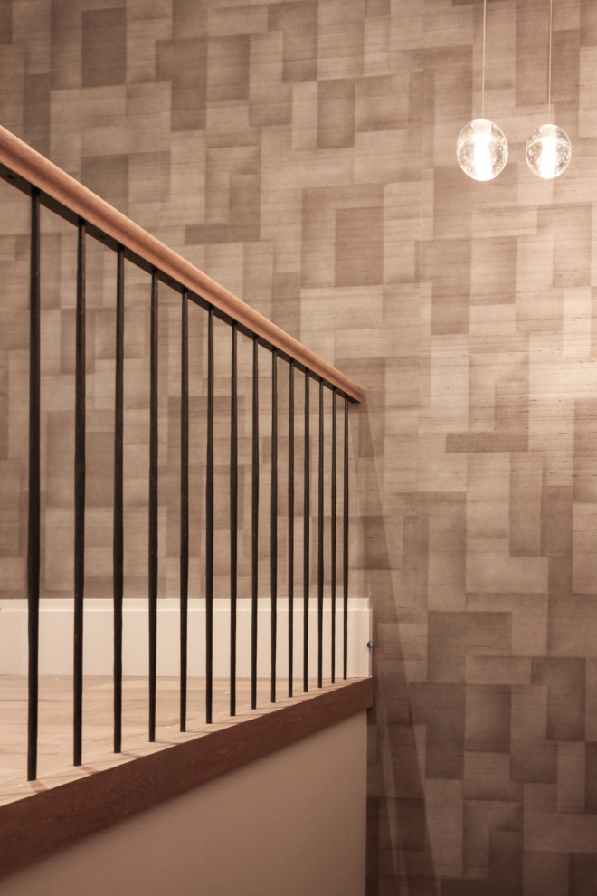 Réalisation d'un grand escalier minimaliste en U avec des marches en bois, des contremarches en bois, un garde-corps en métal et du papier peint.