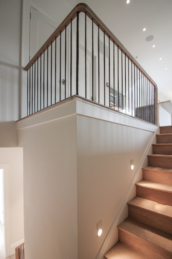 Ejemplo de escalera en U minimalista grande con escalones de madera, contrahuellas de madera, barandilla de metal y papel pintado