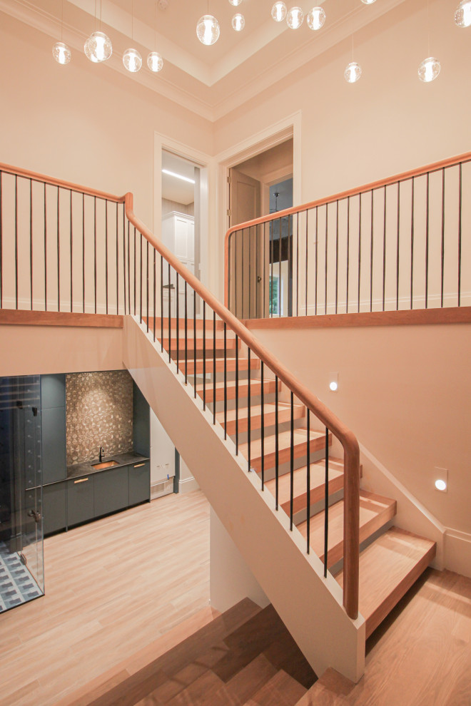 Cette photo montre un grand escalier moderne en U avec des marches en bois, des contremarches en bois, un garde-corps en métal et du papier peint.