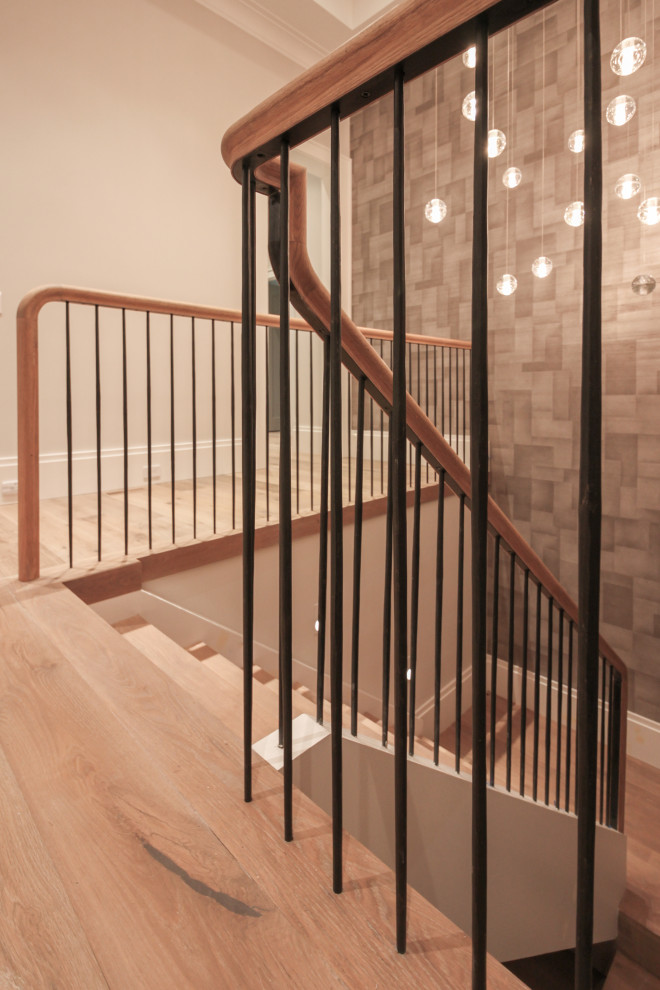 Diseño de escalera en U moderna grande con escalones de madera, contrahuellas de madera, barandilla de metal y papel pintado