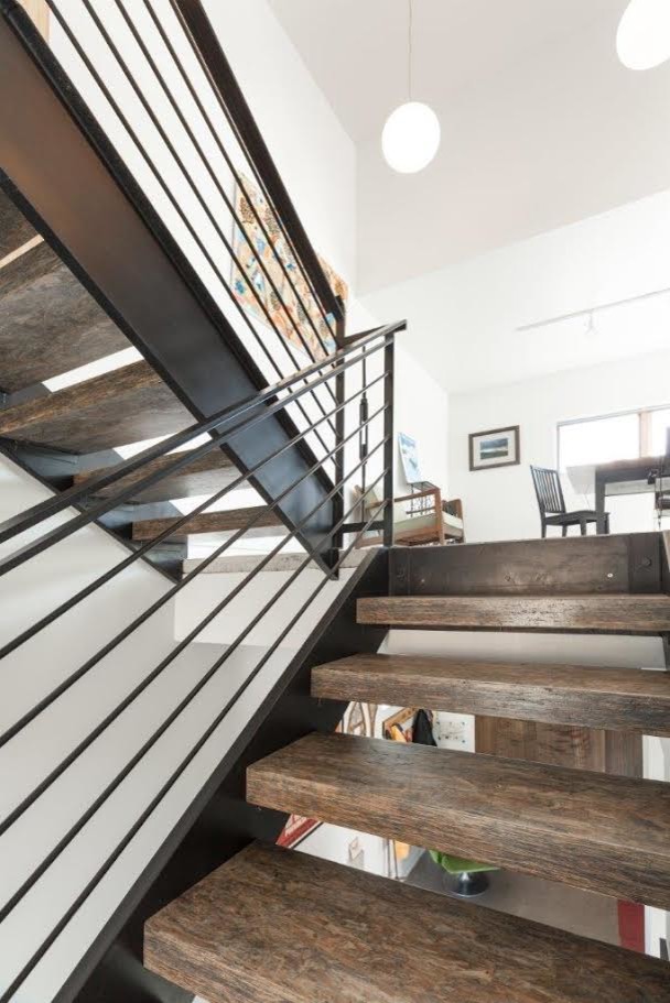 Ejemplo de escalera suspendida actual de tamaño medio sin contrahuella con escalones de madera y barandilla de metal