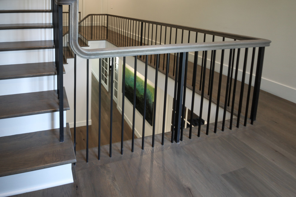 ワシントンD.C.にある高級な広いトランジショナルスタイルのおしゃれなかね折れ階段 (フローリングの蹴込み板、金属の手すり、パネル壁) の写真