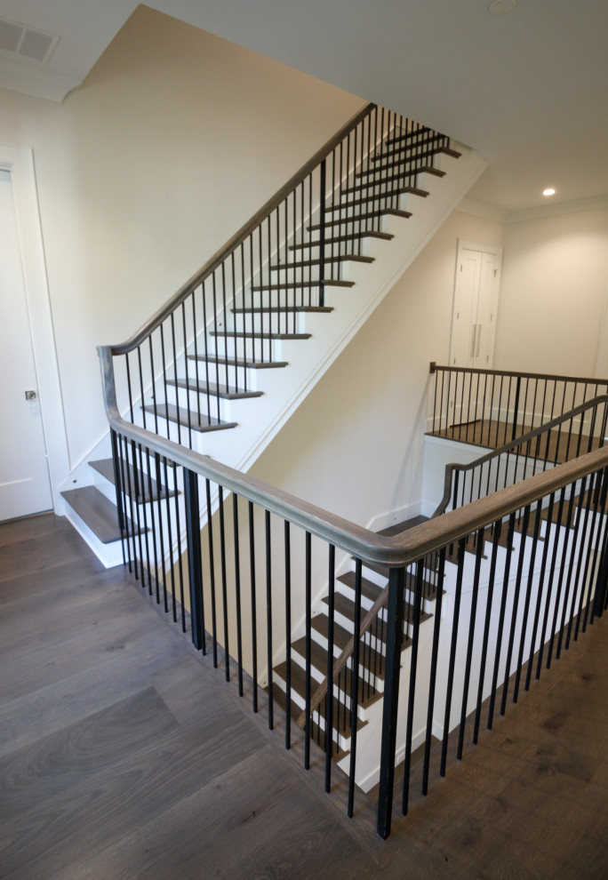 Diseño de escalera en L clásica renovada grande con escalones de madera, contrahuellas de madera pintada, barandilla de metal y panelado