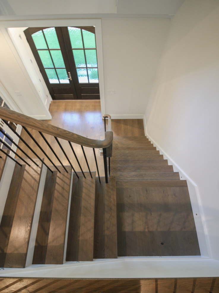 This is an example of a large classic wood l-shaped metal railing staircase in DC Metro with painted wood risers and panelled walls.