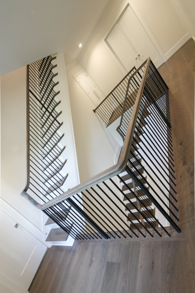Imagen de escalera en L clásica renovada grande con escalones de madera, contrahuellas de madera pintada, barandilla de metal y panelado