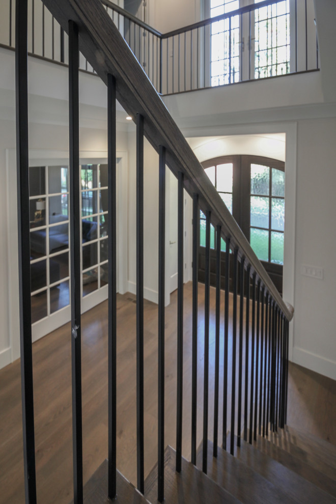 This is an example of a large traditional wood l-shaped metal railing staircase in DC Metro with painted wood risers and panelled walls.