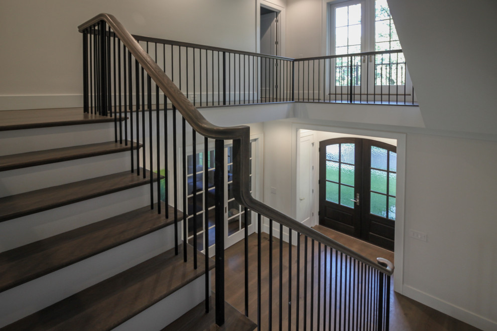 Ejemplo de escalera en L tradicional renovada grande con escalones de madera, contrahuellas de madera pintada, barandilla de metal y panelado