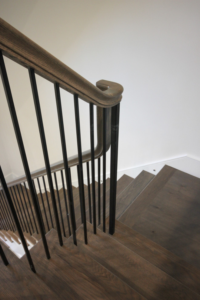 Diseño de escalera en L clásica renovada grande con escalones de madera, contrahuellas de madera pintada, barandilla de metal y panelado