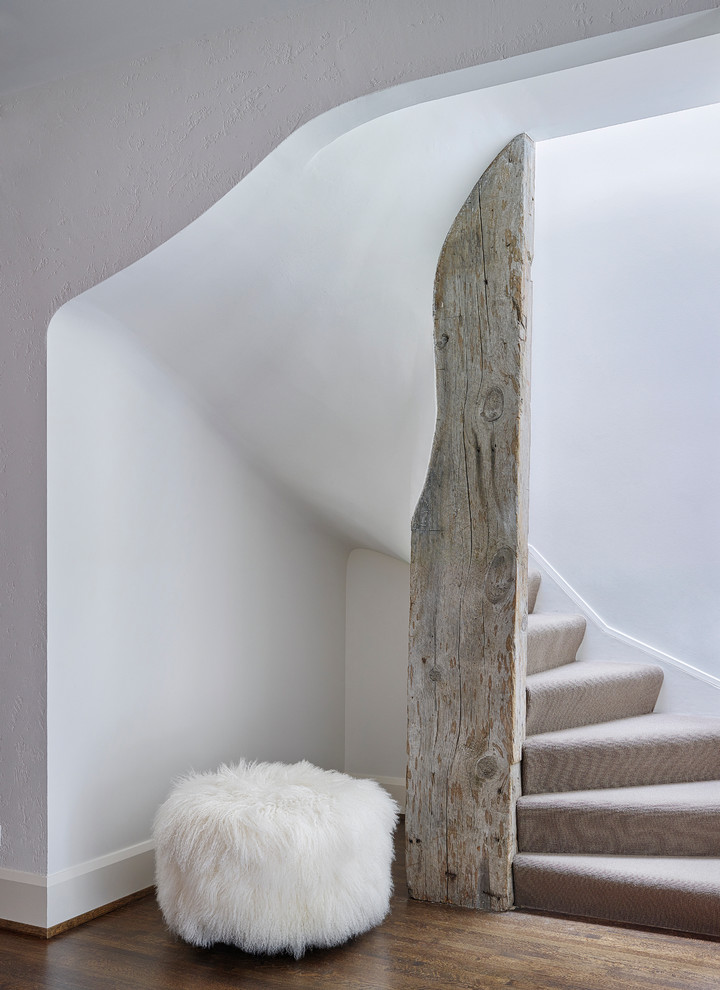 На фото: изогнутая лестница в стиле кантри с ступенями с ковровым покрытием и ковровыми подступенками