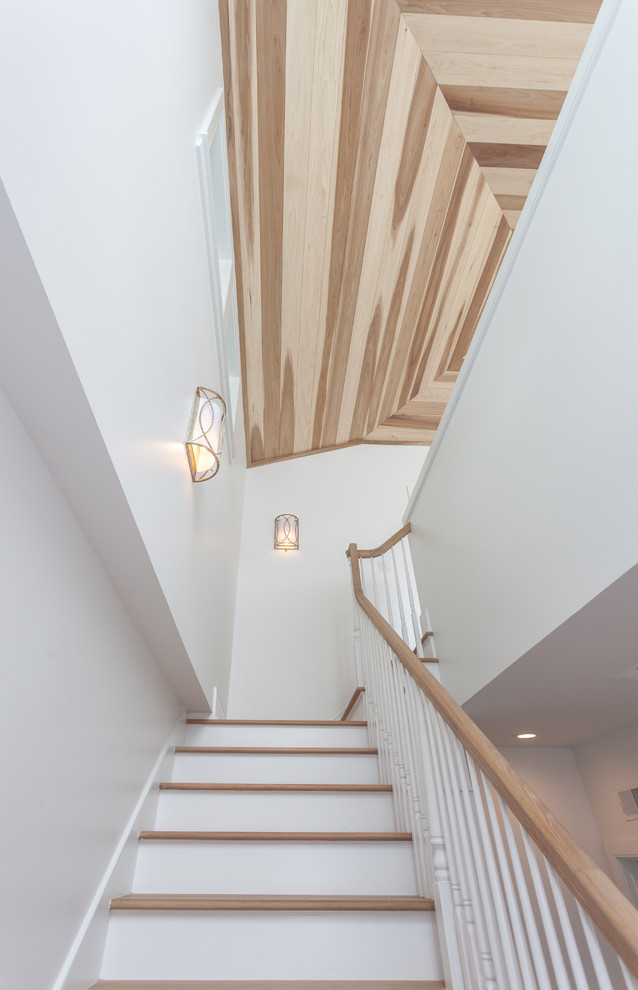 Стильный дизайн: большая п-образная лестница в стиле неоклассика (современная классика) с деревянными ступенями, крашенными деревянными подступенками и деревянными перилами - последний тренд