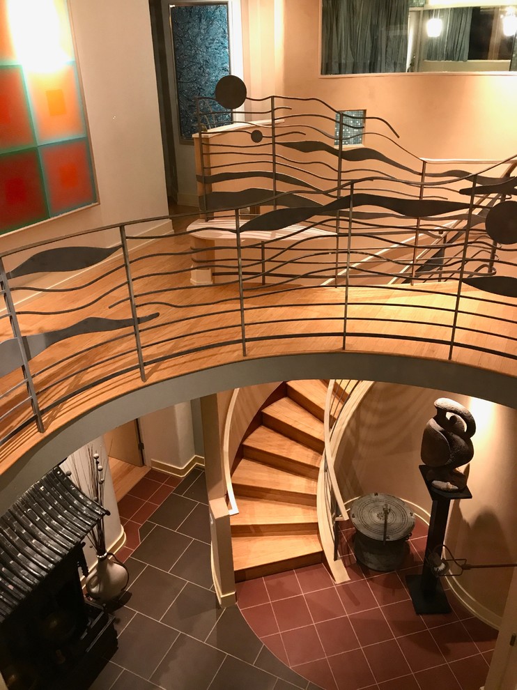 На фото: большая изогнутая деревянная лестница в стиле фьюжн с перилами из смешанных материалов и деревянными ступенями с