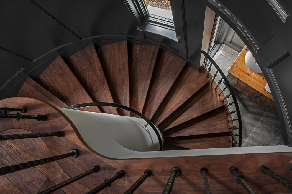 Imagen de escalera curva de estilo de casa de campo grande con escalones de madera y barandilla de metal
