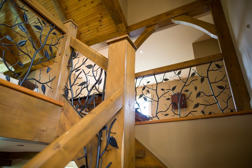 Foto på en stor rustik l-trappa i trä, med räcke i metall