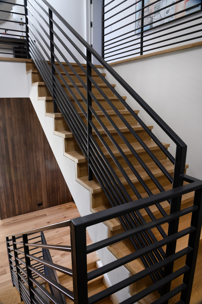 Aménagement d'un escalier moderne en L avec des marches en bois, des contremarches en bois et un garde-corps en métal.