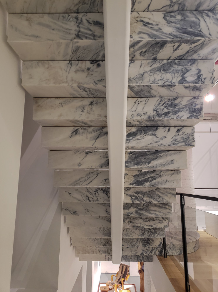 Cette photo montre un très grand escalier flottant moderne en marbre avec des contremarches en marbre.