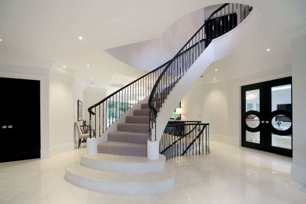 Пример оригинального дизайна: изогнутая лестница в стиле неоклассика (современная классика) с ступенями с ковровым покрытием и ковровыми подступенками