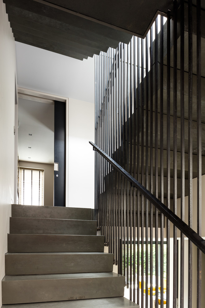 Стильный дизайн: большая п-образная бетонная лестница в современном стиле с бетонными ступенями и металлическими перилами - последний тренд