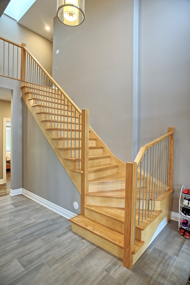 На фото: изогнутая деревянная лестница среднего размера в стиле модернизм с деревянными ступенями и перилами из смешанных материалов