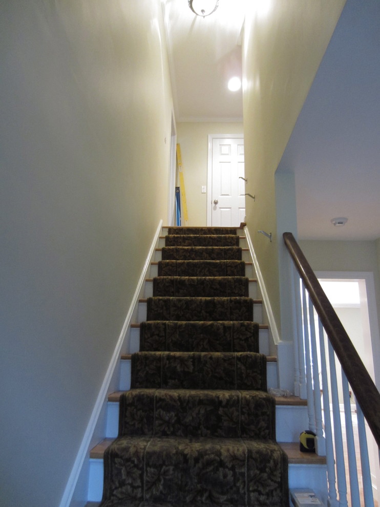 Photo of a medium sized traditional concrete straight staircase in New York with carpeted risers.