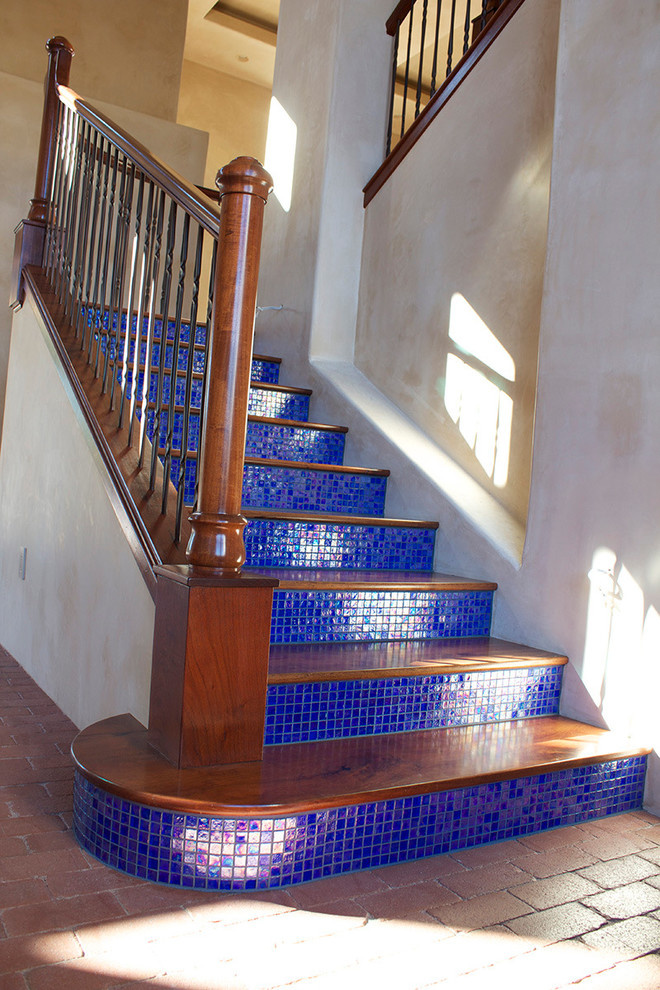 На фото: прямая лестница в средиземноморском стиле с деревянными ступенями и подступенками из плитки с