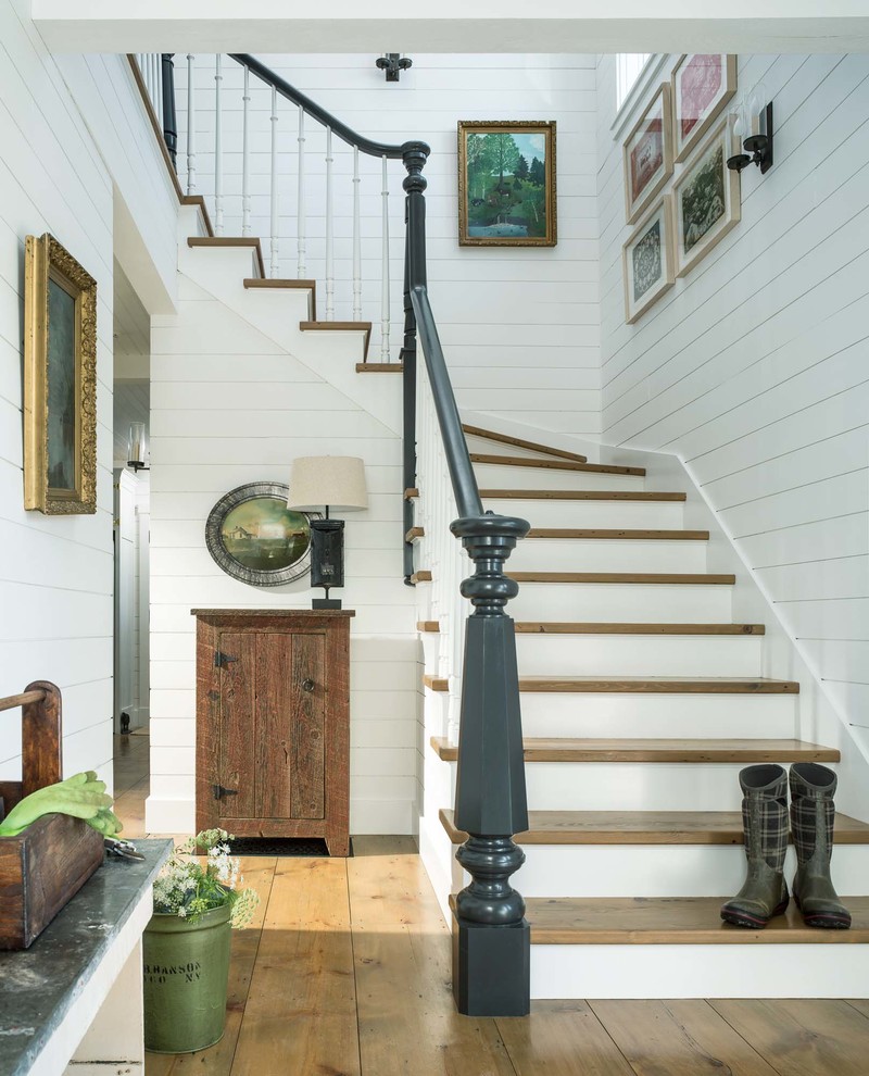 Стильный дизайн: изогнутая деревянная лестница в стиле кантри с деревянными ступенями и деревянными перилами - последний тренд