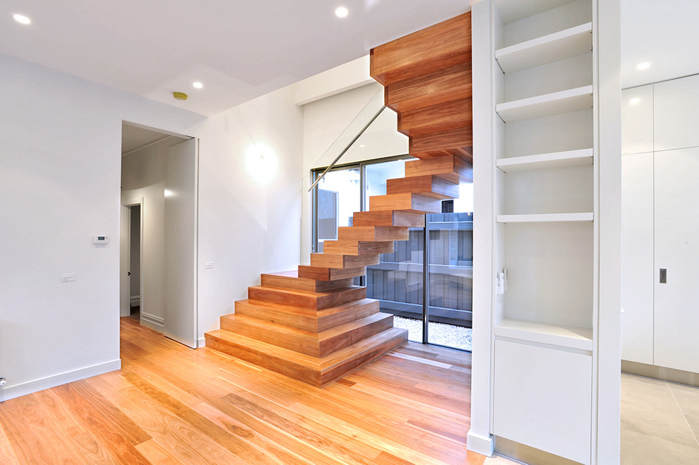 На фото: деревянная лестница на больцах, среднего размера в современном стиле с деревянными ступенями с