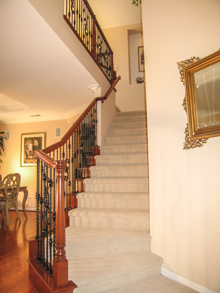 This is an example of a medium sized traditional carpeted l-shaped staircase in Orange County with carpeted risers.