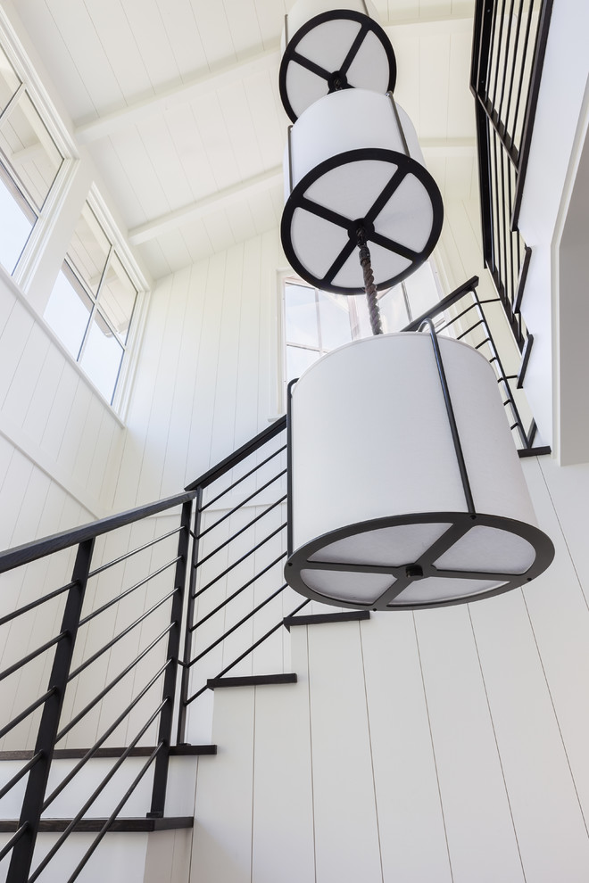 Réalisation d'un escalier minimaliste en L avec des marches en bois, des contremarches en bois et un garde-corps en métal.