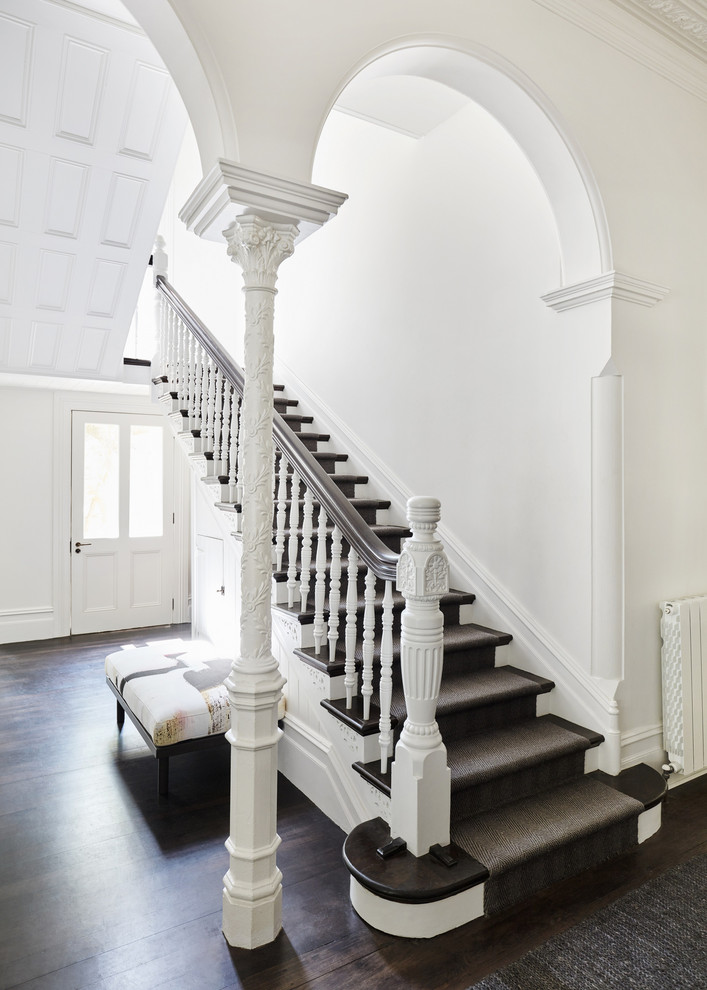 На фото: большая п-образная лестница в викторианском стиле с деревянными ступенями, крашенными деревянными подступенками и деревянными перилами