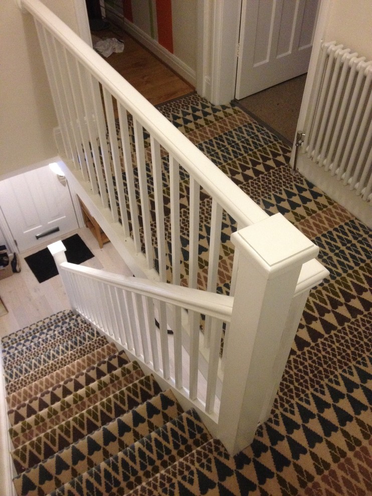 Idée de décoration pour un escalier droit minimaliste de taille moyenne avec des marches en moquette, des contremarches en moquette et un garde-corps en bois.