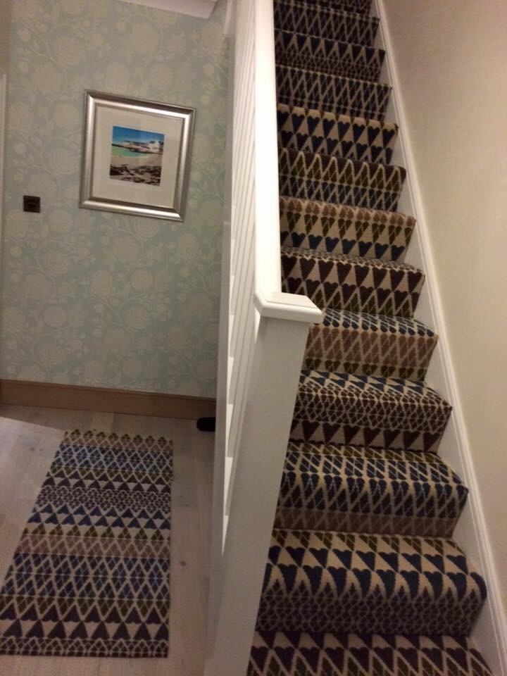 Imagen de escalera recta minimalista de tamaño medio con escalones enmoquetados, contrahuellas enmoquetadas y barandilla de madera
