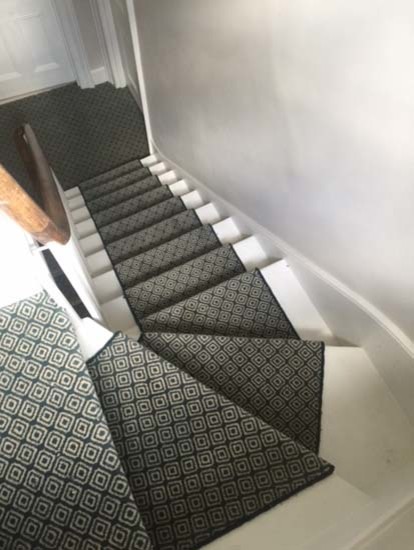 Идея дизайна: изогнутая лестница среднего размера в современном стиле с ступенями с ковровым покрытием, ковровыми подступенками и деревянными перилами