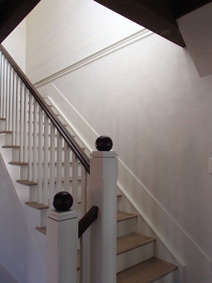 This is an example of a medium sized country wood straight staircase in Denver with painted wood risers.